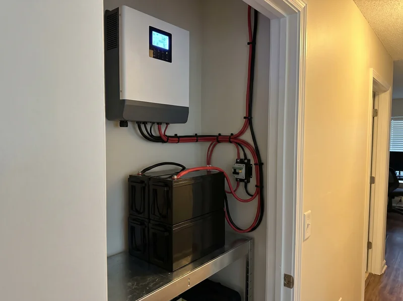 Інвертор з LCD-дисплеєм на стіні та два LiFePO4 акумулятори на стелажі в коморі квартири — приклад акуратного монтажу резервного живлення